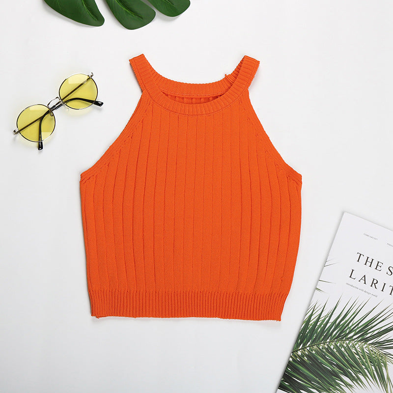 Orange ribbed halter crop top flatlay with monstera leaf and minimal styling