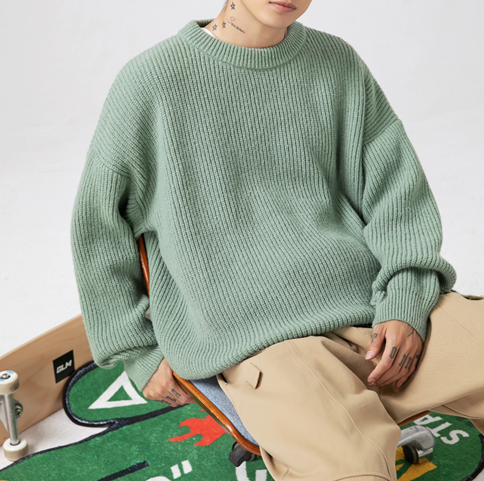Sage green ribbed sweater paired with khaki cargo pants and skateboard, casual streetwear styling