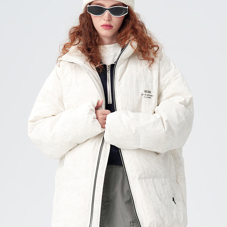 Close-up portrait of woman with red curly hair wearing white puffer jacket, white beanie and slim sunglasses against white background