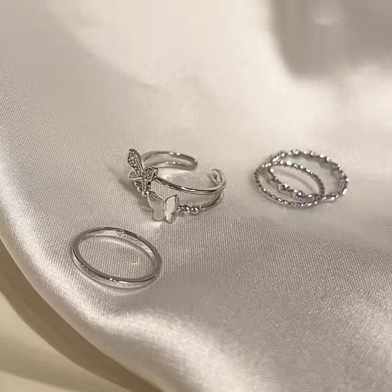 Silver rings with butterfly theme on white fabric, adjustable and textured stackable jewelry pieces