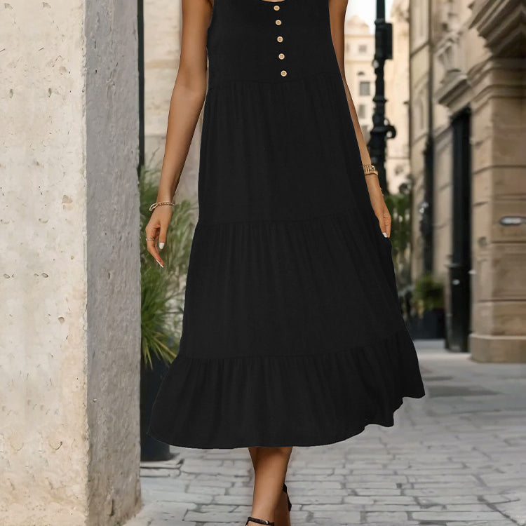 Black sleeveless midi dress with gold buttons, model standing on cobblestone street, wearing black high heels