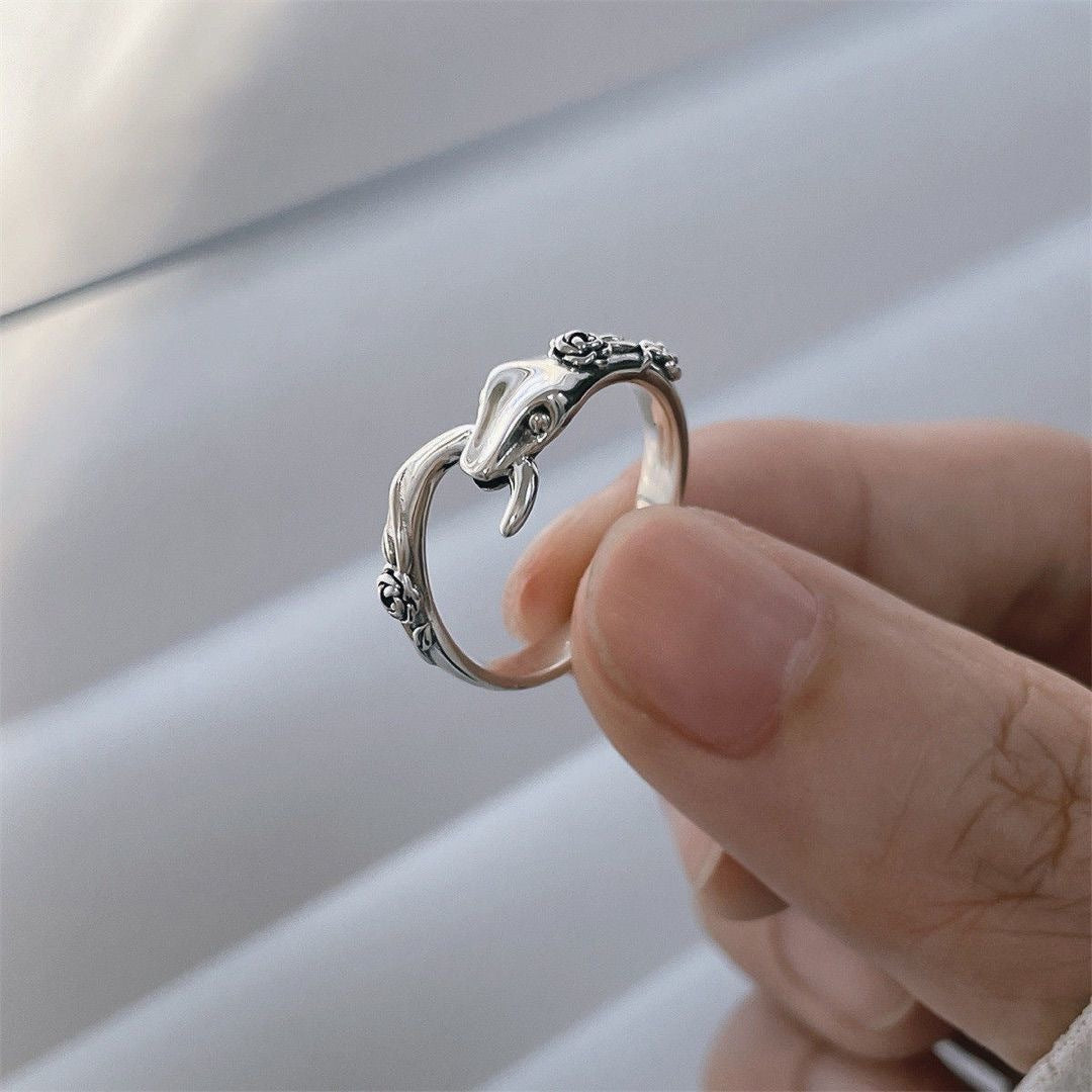A model is holding a sterling silver snake ring between thumb and index finger against white background