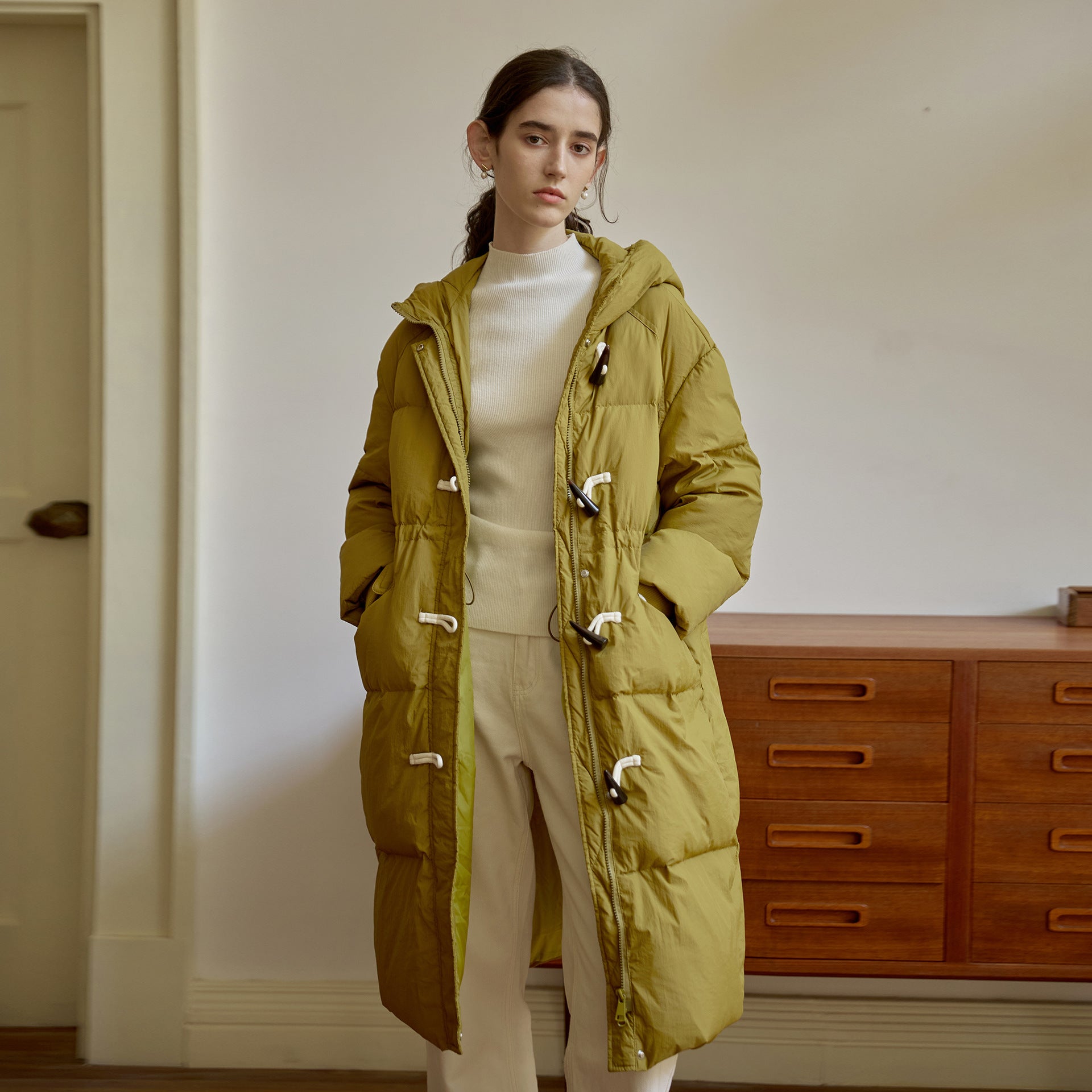 Olive green winter puffer coat with toggle closures and hood, paired with cream separates