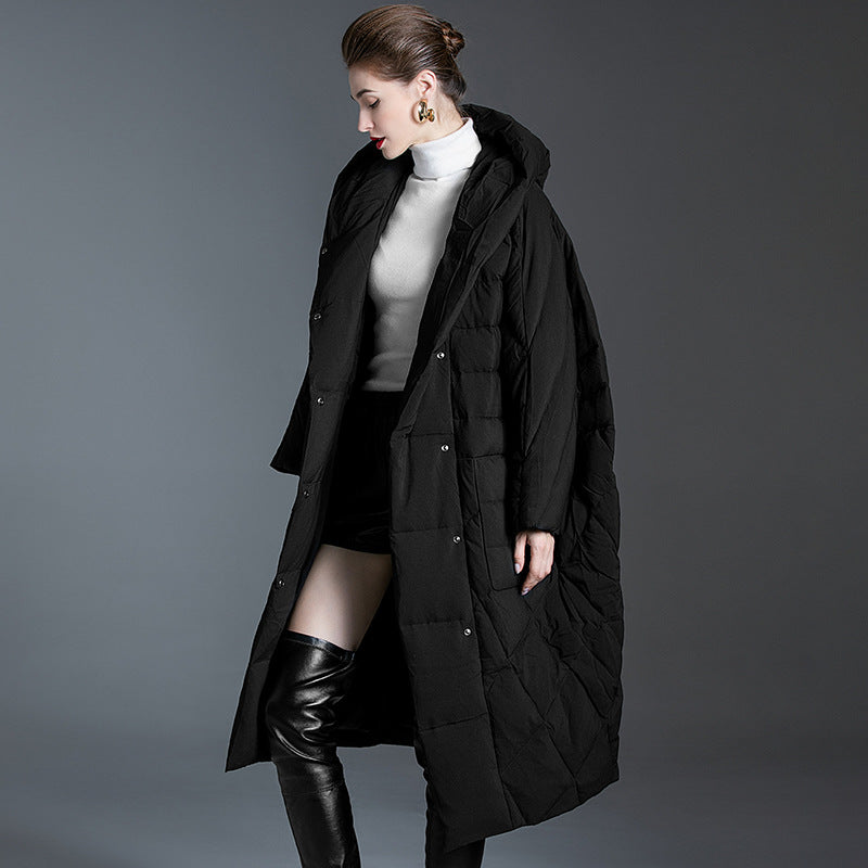 Side profile of black quilted down coat showing elegant styling with white turtleneck, statement earrings and knee boots