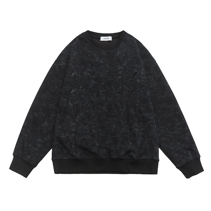A black washed oversized sweatshirt with embossed text laid flat, showcasing the textured design and ribbed cuffs
