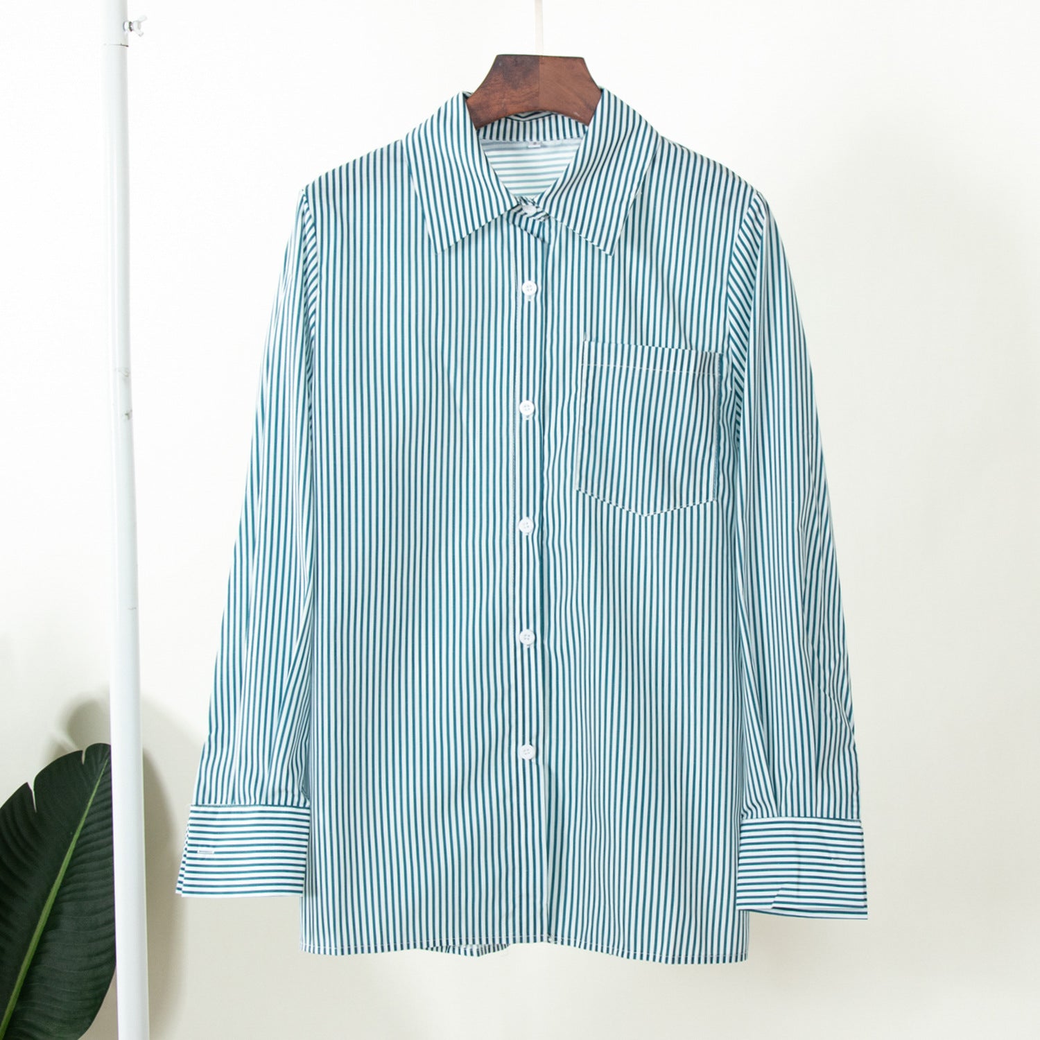 Teal and white striped long-sleeve shirt hanging on display