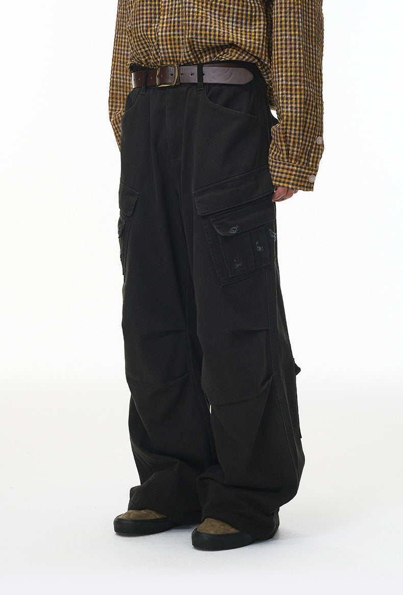 Person wearing black cargo pants with a plaid shirt on a white background