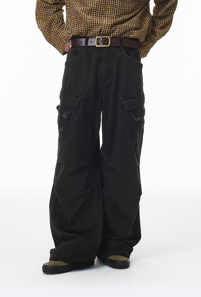 Person wearing black cargo pants and a patterned shirt on a white background