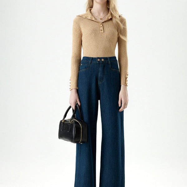 Model standing in beige ribbed sweater and dark blue wide leg cropped jeans.