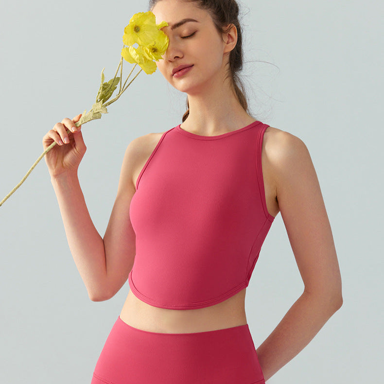 Woman in brick red high-neck crop top and leggings holding a yellow flower to her face.