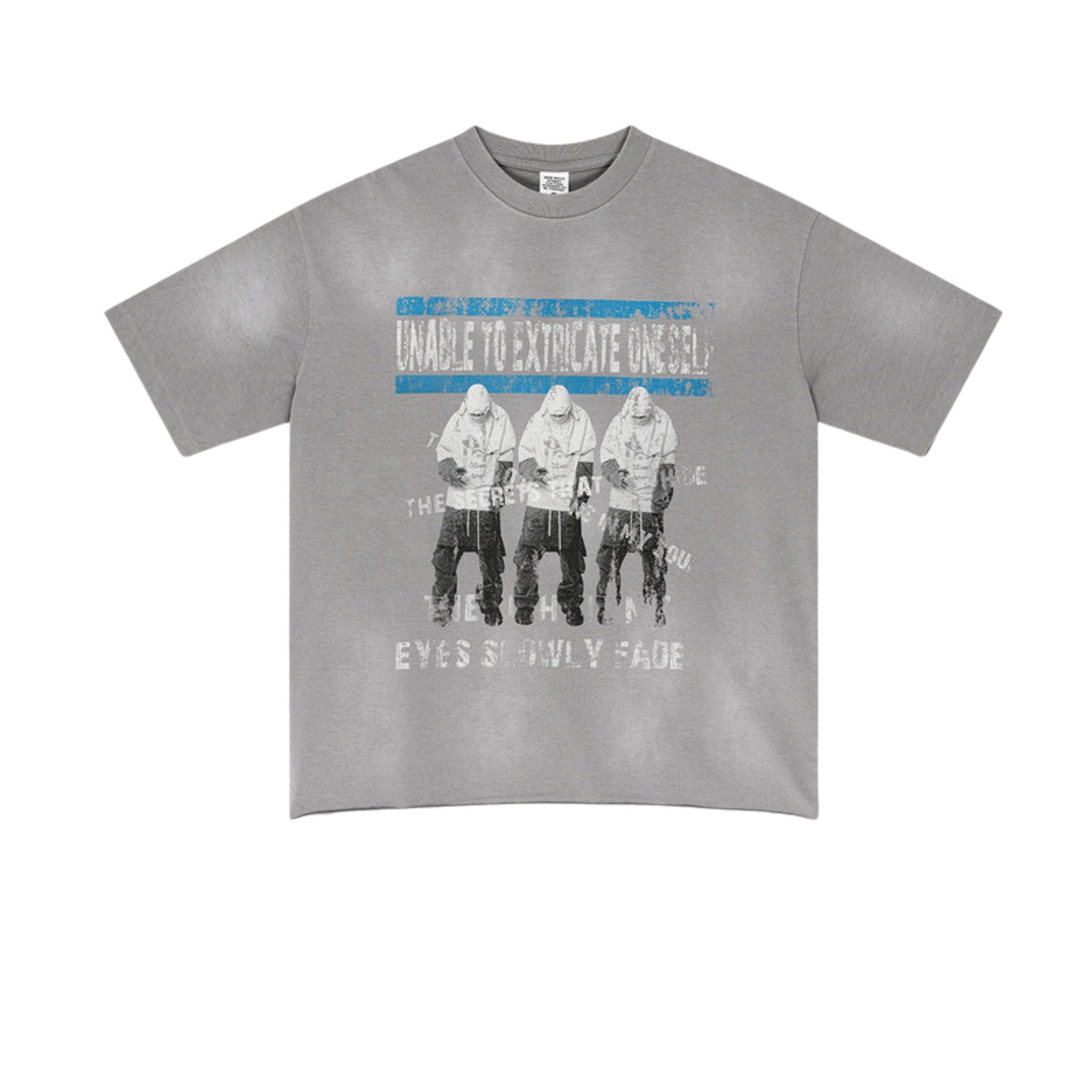 Flat lay of gray oversized graphic tee with distressed print of three hooded figures and faded text.