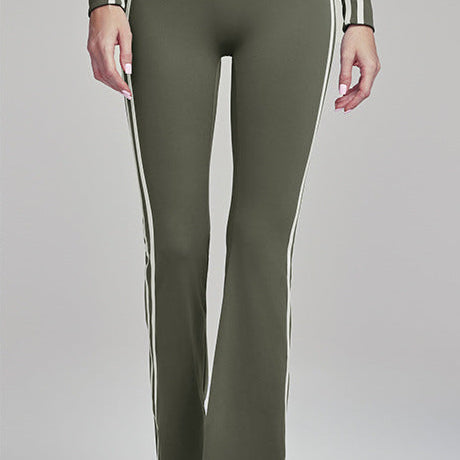 Woman wearing army green flare leggings with white side stripes.