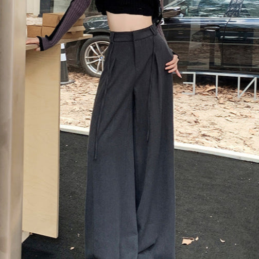 Model wearing gray flowy drawstring trousers styled with cropped ribbed sweater and beanie.