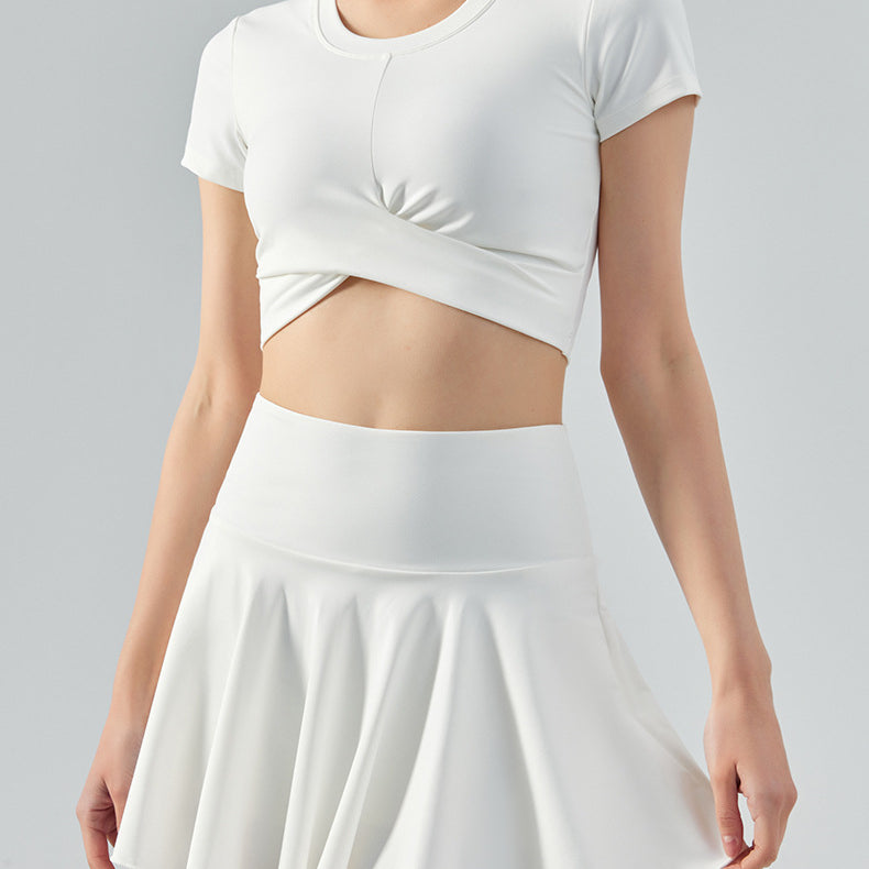 Woman wearing white tennis set with short-sleeve crop top and high-waist flared skirt.