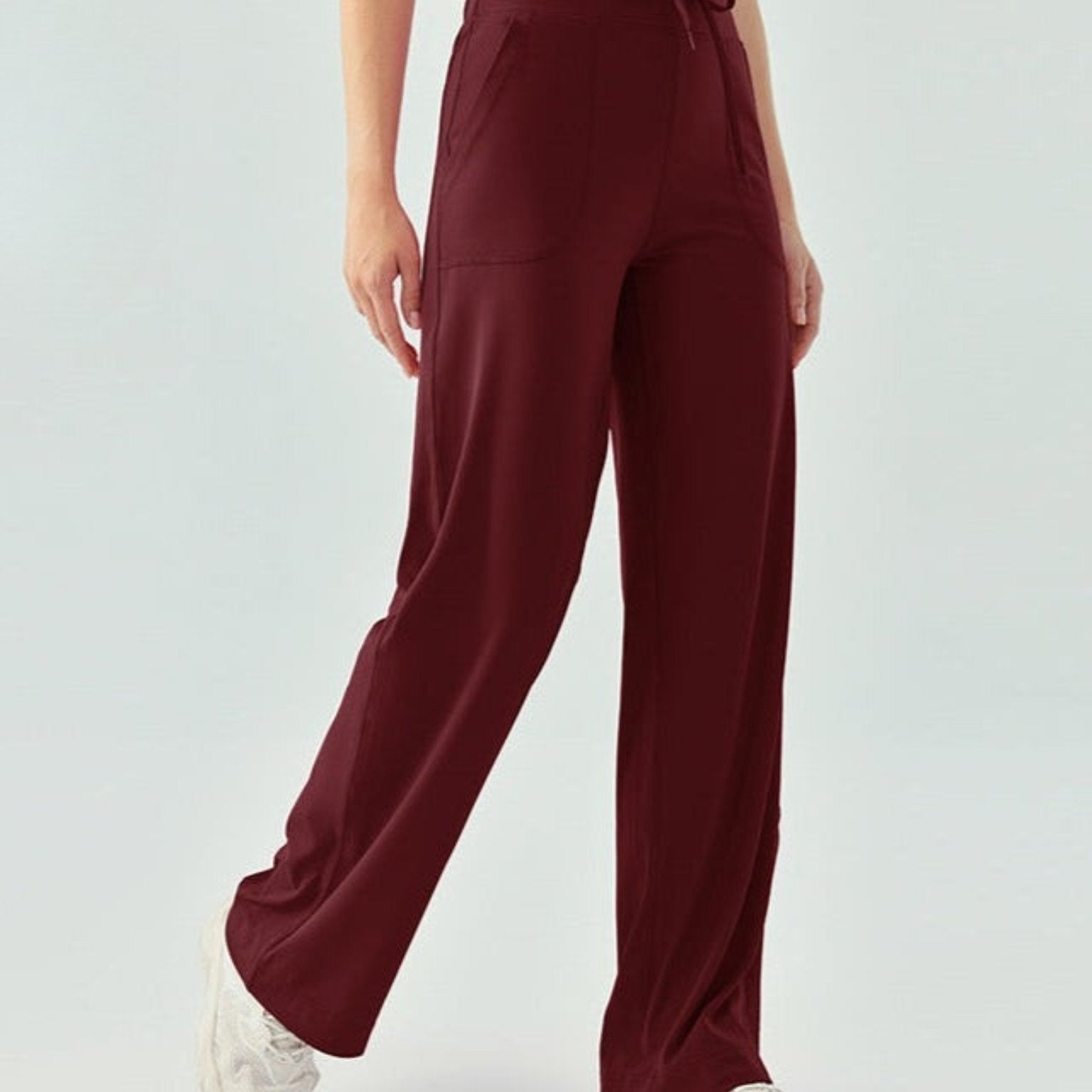 Woman wearing high-waisted wine berry yoga pants with drawstring waist and wide legs.