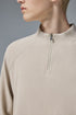 Close-up of a person wearing khaki half zip long sleeve t shirt against a gray background