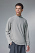 Man wearing a light gray half-zip long-sleeve tshirt on a gray background