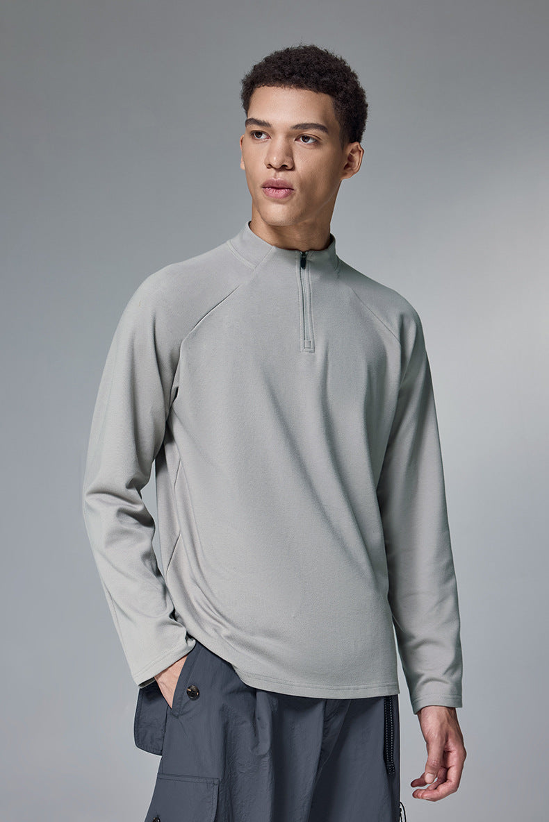 Man wearing a light gray half-zip long-sleeve tshirt on a gray background
