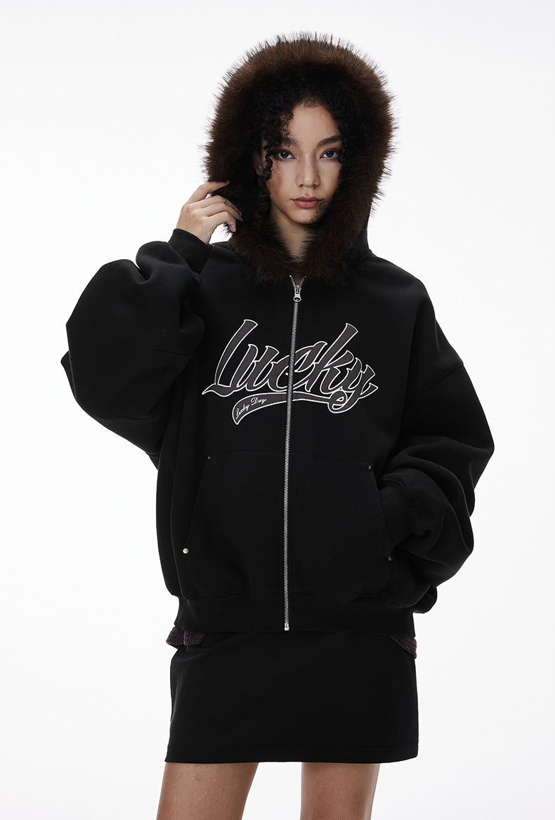 Female model in black jacket with hood up, mid-length view.