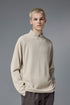 Man wearing khaki half zip long sleeve t shirt styled with brown pants