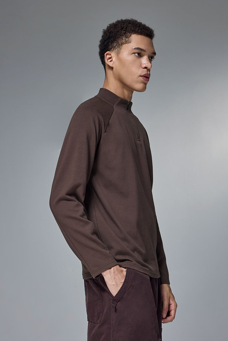 Man wearing a brown long-sleeve tshirt against a gray background