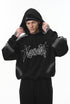 Male model adjusting hood, black graphic hoodie, relaxed front view.
