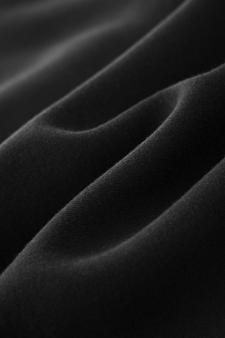 Soft brushed fleece fabric drape of black hoodie, texture close-up.