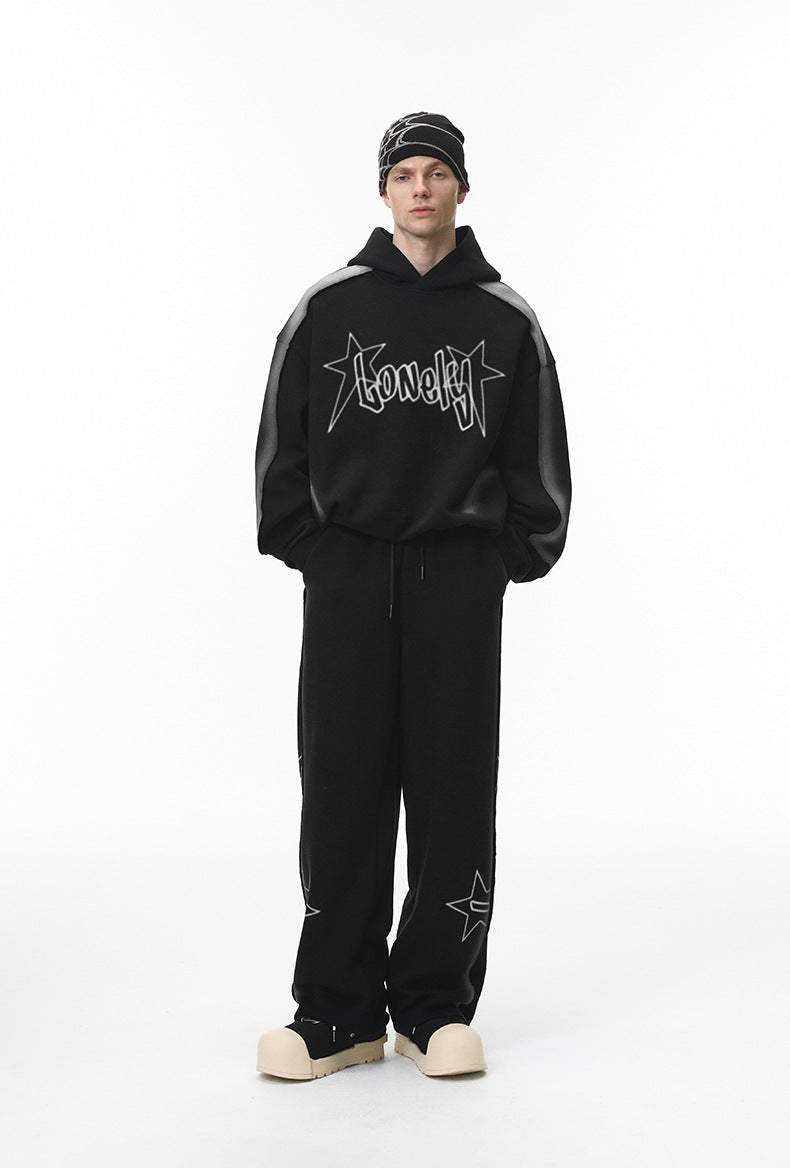 Full body male model in black graphic hoodie and matching sweatpants, front.