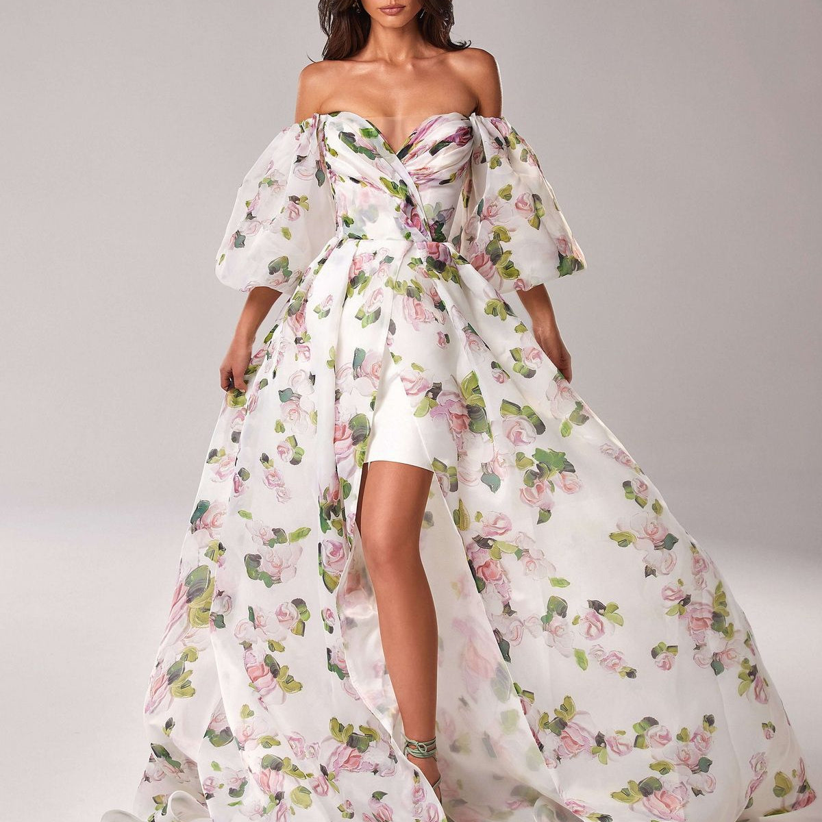Woman in pink off-shoulder puff sleeve floral gown with high slit and sweetheart neckline.