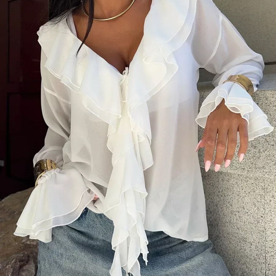 Ruffled white blouse with V-neck and layered sleeves styled with light jeans.