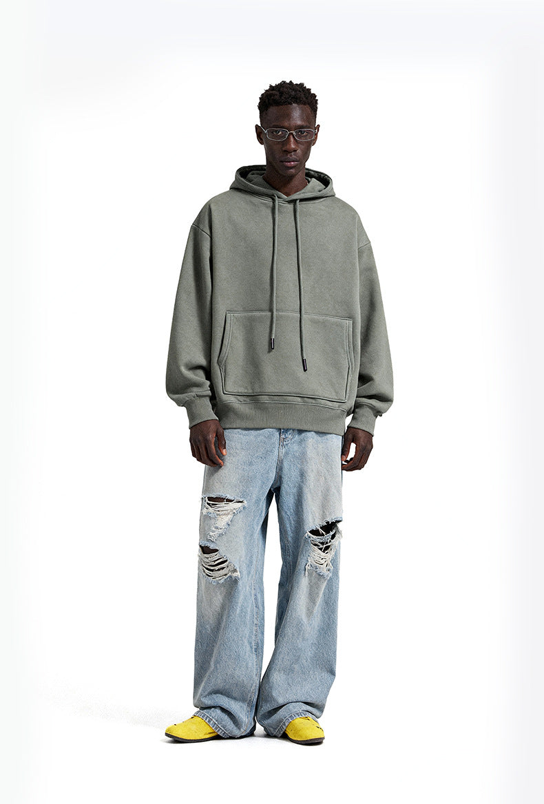 Person wearing sage hoodie and light blue jeans with a white background