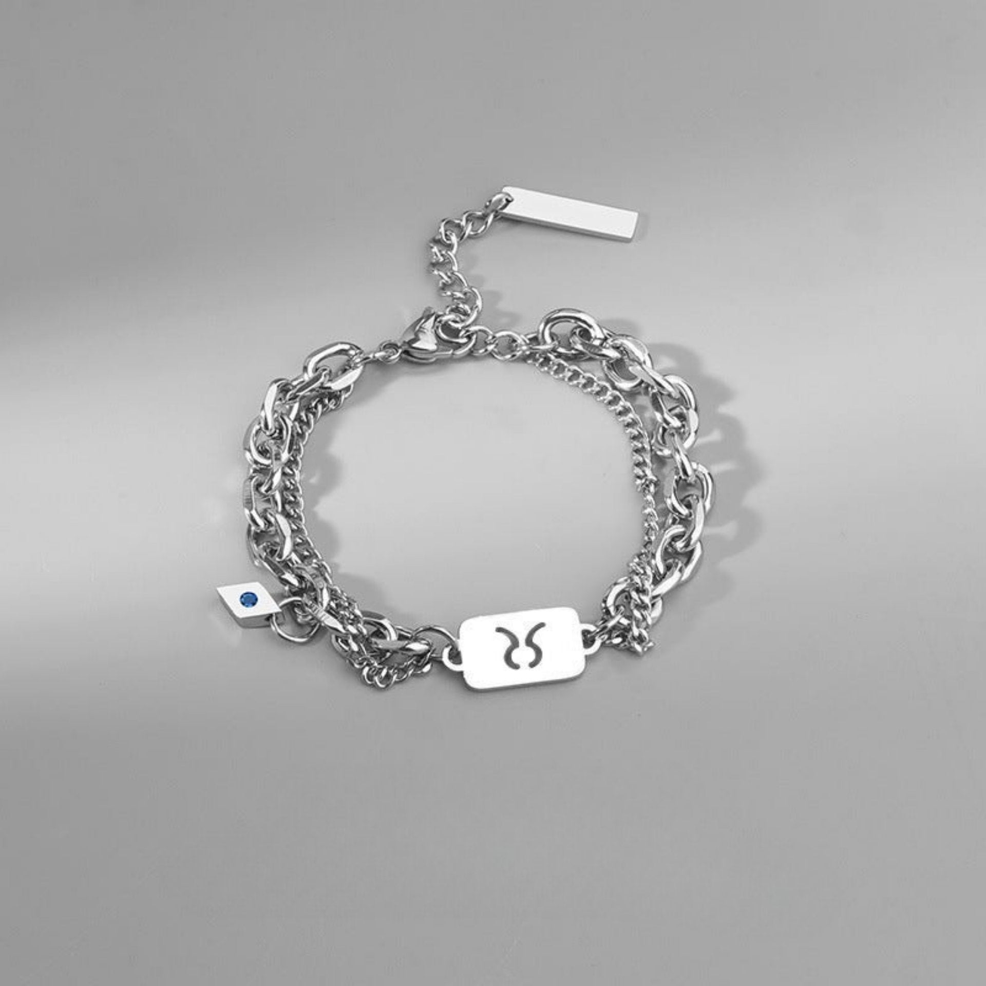 Taurus zodiac charm bracelet with a silver-tone layered chain and an engraved zodiac symbol pendant.