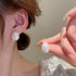 Opalescent pearl stud earring shown on ear and held by manicured hand showing iridescent finish