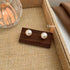 12mm pearl stud earrings displayed on wooden holder against textured burlap fabric background