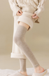 Beige ribbed knit thigh-high leg warmers layered over cuffed sweater dress