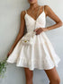 White cotton sundress with tiered skirt, spaghetti straps, and fitted bodice, styled with quilted mini bag and delicate floral accessories