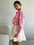 White spaghetti strap sundress with tiered skirt, layered with pink denim jacket and styled with chic smartphone and floral accessories