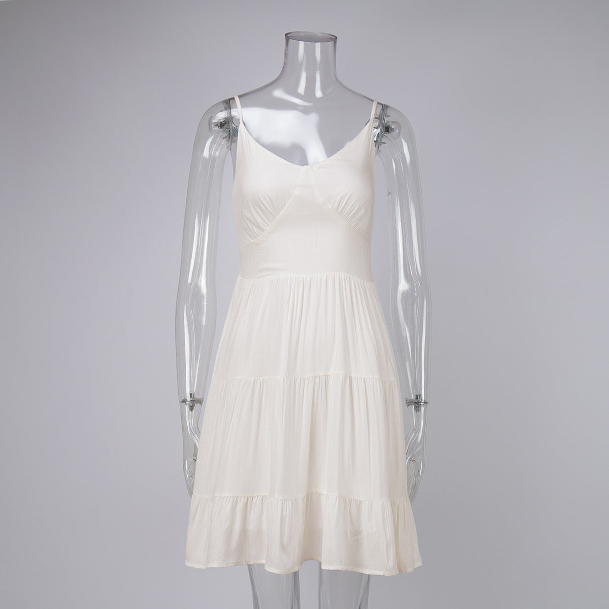 White spaghetti strap sundress with fitted bodice and flowy tiered skirt, styled with pink denim jacket and white sneakers