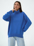 Model in relaxed blue turtleneck sweater, dropped shoulders, paired with light wash jeans