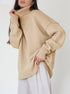 Beige chunky knit turtleneck sweater, model styled with white wide-leg pants, elegant look
