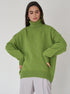 Sage green oversized turtleneck, model posing thoughtfully, modern casual winter fashion