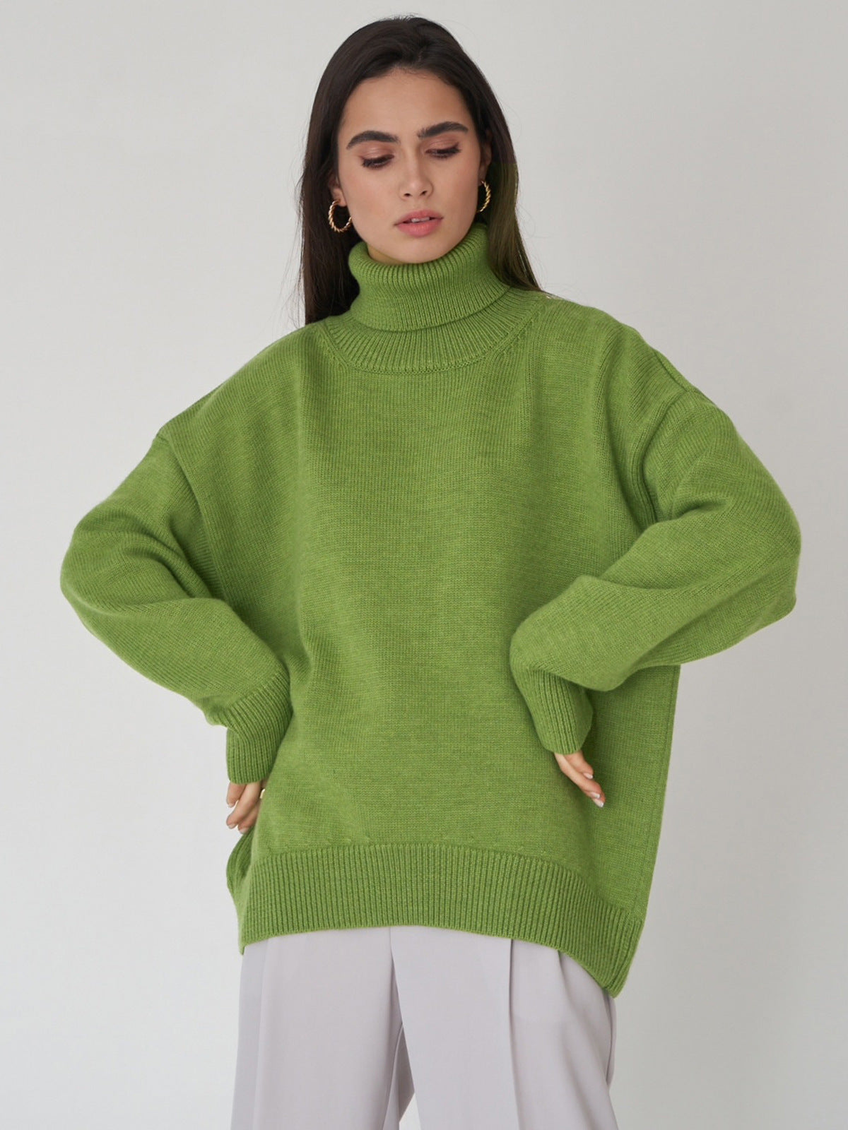 Sage green oversized turtleneck, model posing thoughtfully, modern casual winter fashion