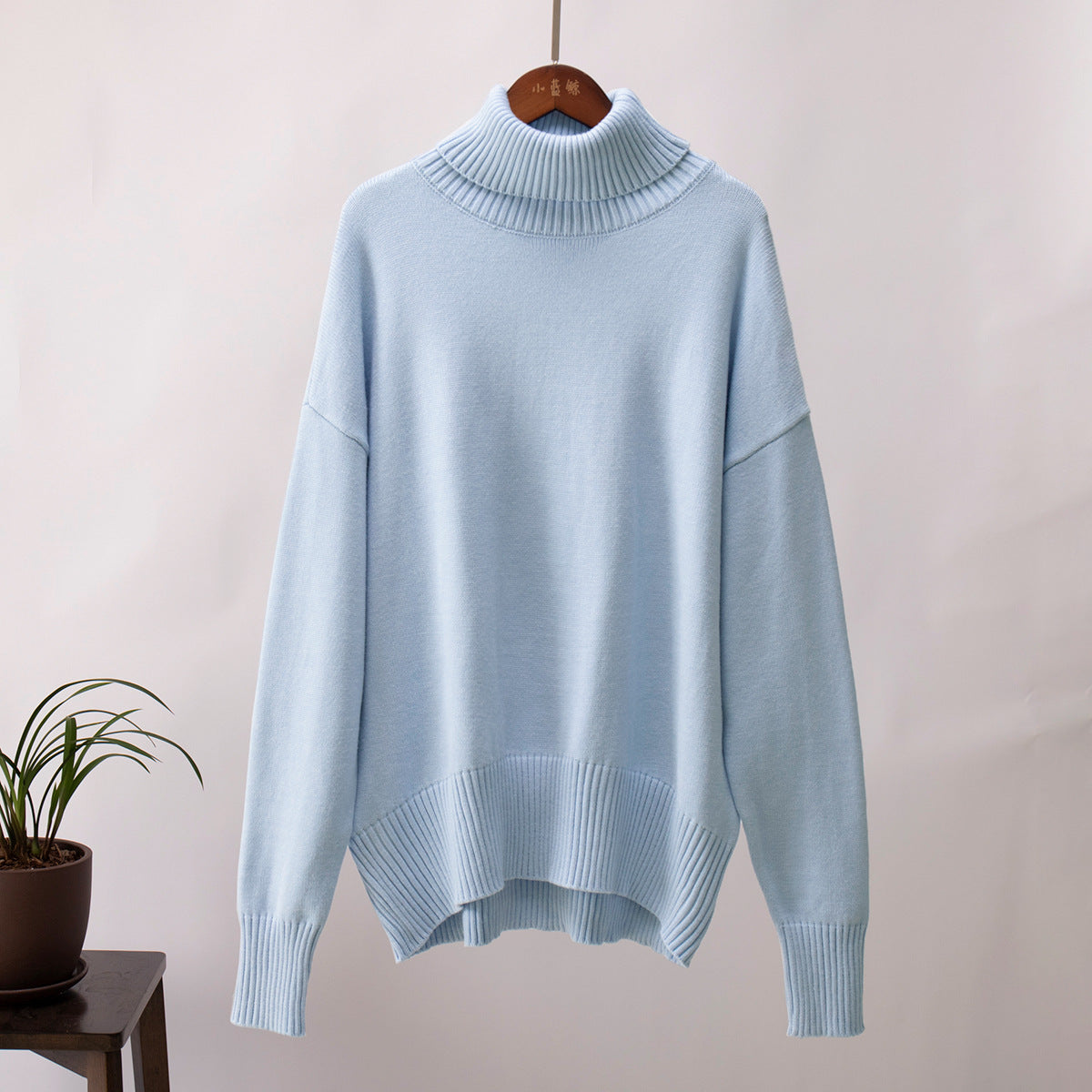 Soft pastel blue turtleneck on hanger, relaxed fit with ribbed details, minimalist style