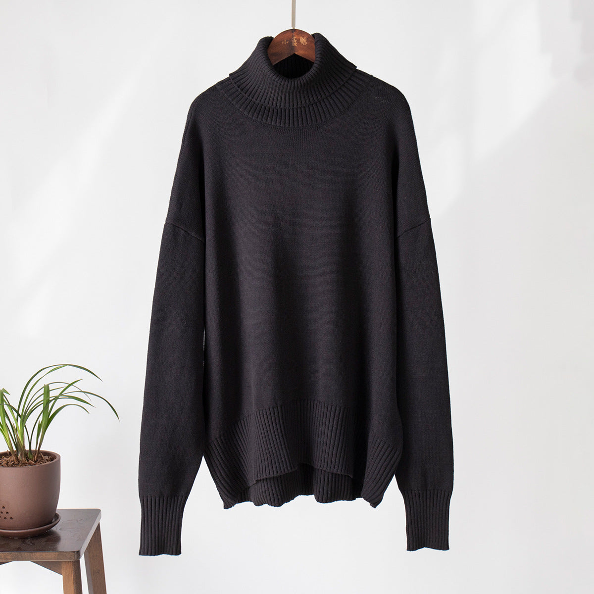 Charcoal black turtleneck sweater, wooden hanger, thick ribbed collar, modern aesthetic