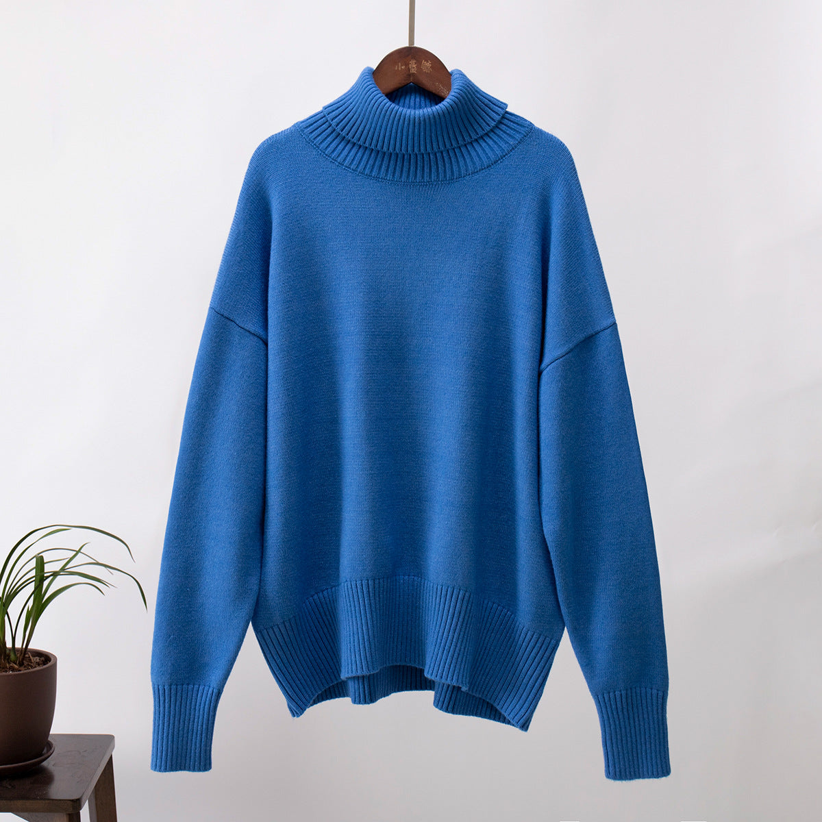 Royal blue turtleneck sweater hanging, soft knit fabric, minimalist product shot