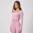 Soft pink athletic two-piece set with scoop neck crop top, front tie detail, white trim and high-waisted leggings with ruched waistband detail