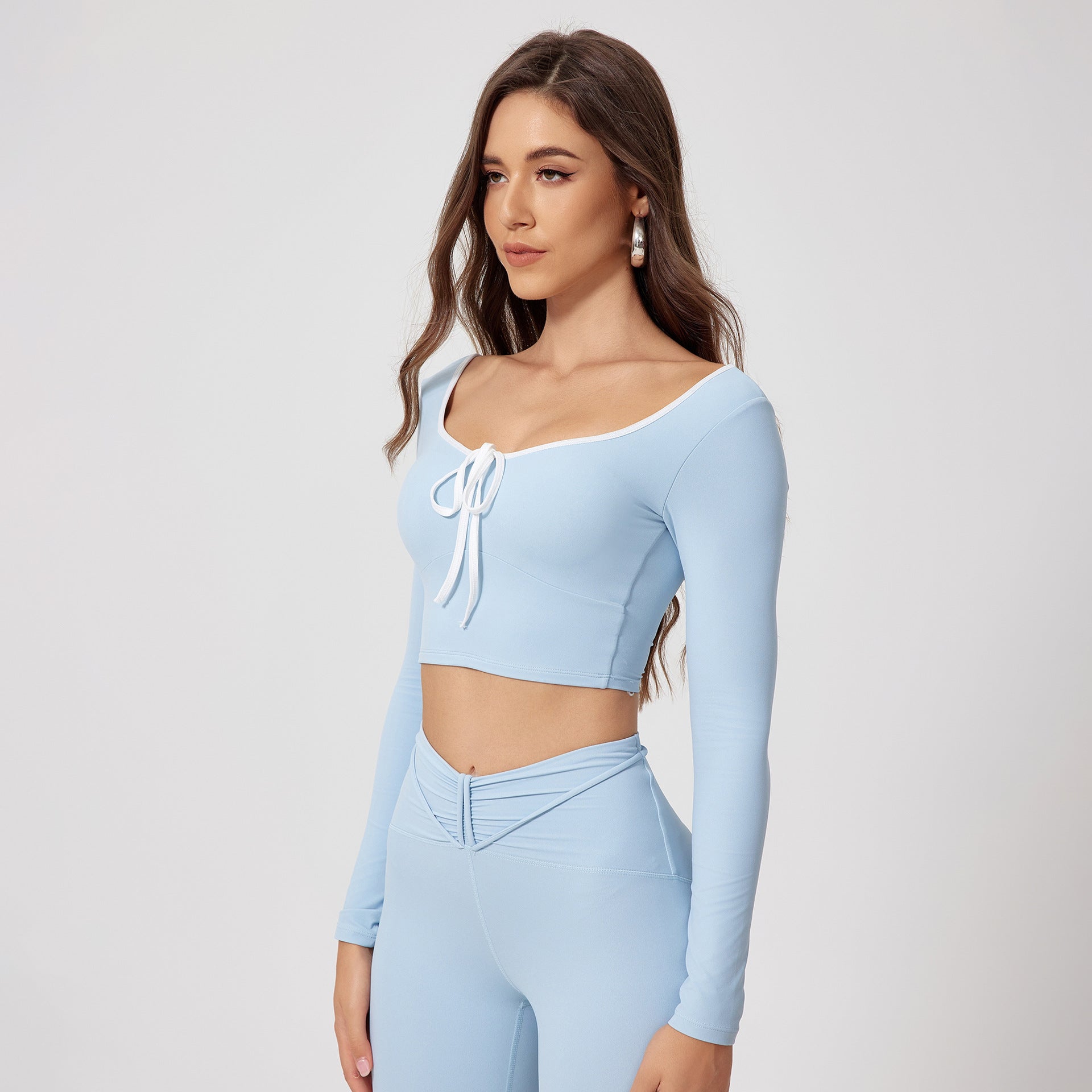 Baby blue workout set featuring long sleeve crop top with white piping, tie front detail and matching high-waisted athletic leggings with V-shaped waistband