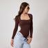 Model wearing brown long-sleeve bodysuit with lace trim neckline and light jeans, posing against white background, side profile view