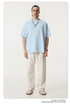 Model in light blue oversized t-shirt paired with cream drawstring pants and beige shoes, accessorized with silver chain necklace