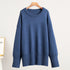 A navy blue oversized sweater displayed on wooden hanger against white wall. Relaxed fit with ribbed trim details and drop shoulders